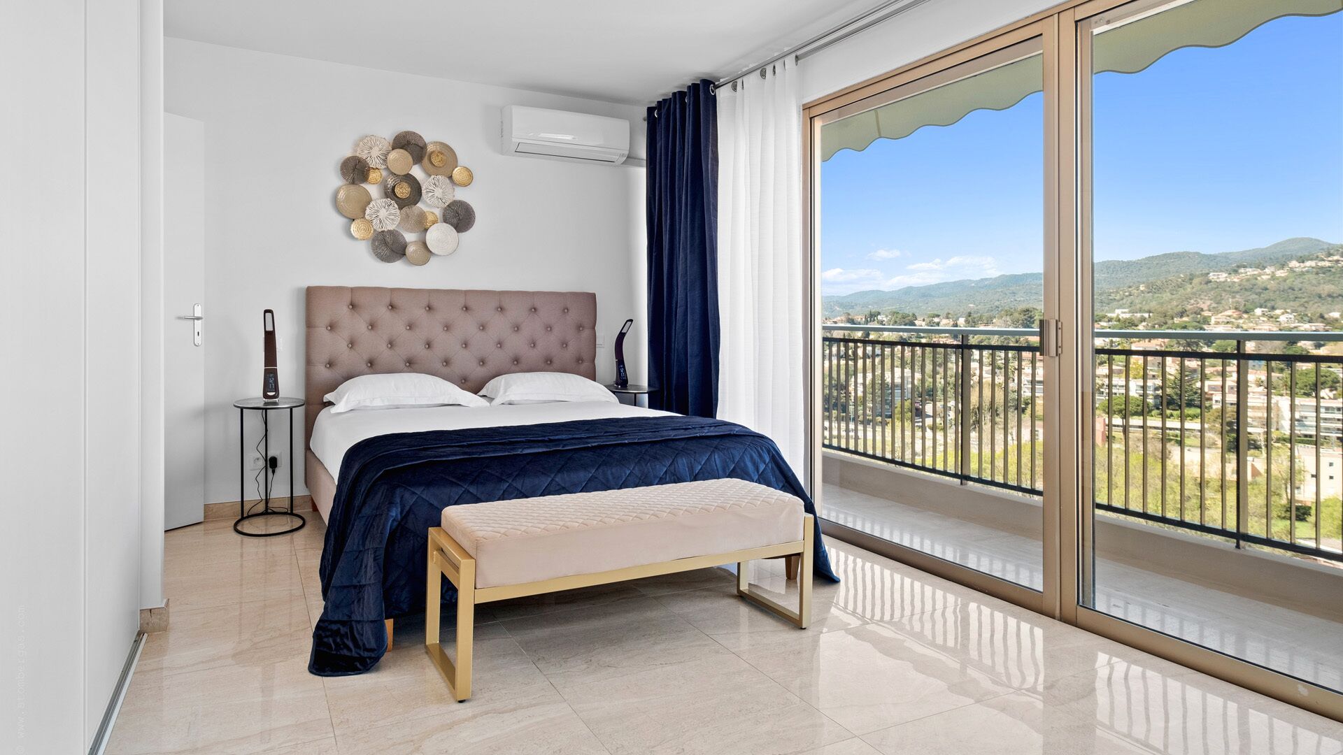 Une chambre à coucher avec un lit, une table de chevet et une vue sur un balcon doté d’une balustrade.