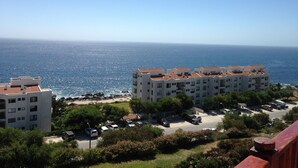 Zona residencial costera con edificios de apartamentos, un estacionamiento y vista al mar.