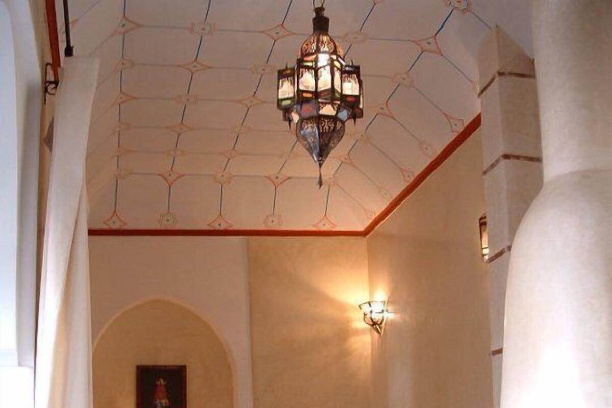 A room with two beds, a chandelier, a wall-mounted lamp, and a fireplace.