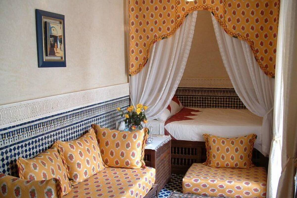 A room with a bed, a sofa, and a patterned rug.