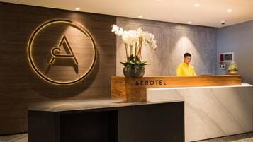 Una mesa de recepción con un logotipo, una planta en maceta y una placa con el nombre 'AEROTEL'.