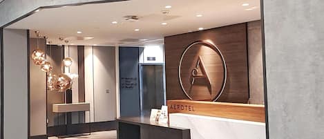 The entrance of the Aerotel Airport Hotel with a reception desk, a large illuminated 'A' sign, and a modern interior design.