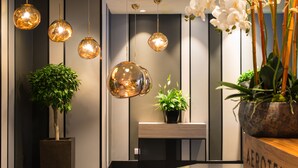 Un espace d’accueil comprenant un comptoir de réception, des plantes en pot et des luminaires sphériques suspendus.