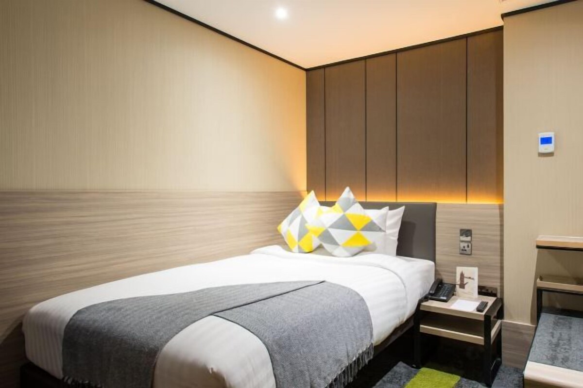 Une chambre d’hôtel comprenant un lit, une table de chevet et un petit bureau.