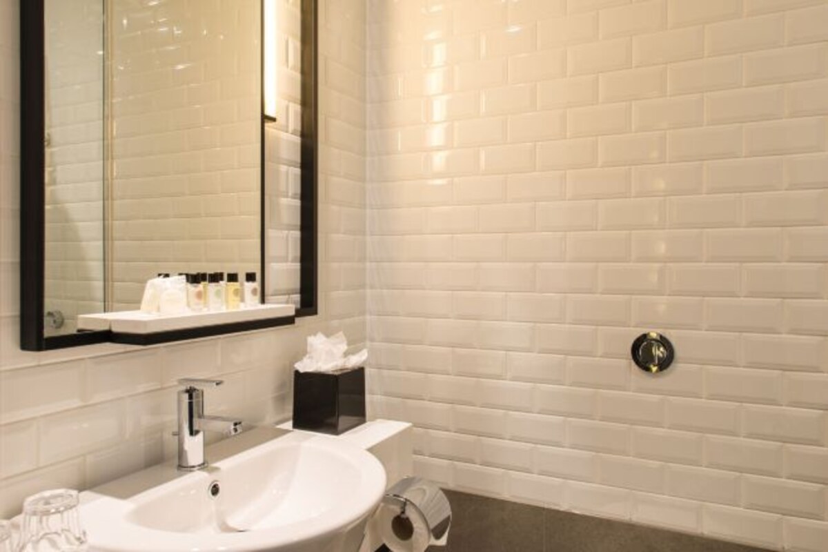 A bathroom with a white sink, a mirror, and a toilet.