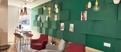 A modern interior with green walls, multiple seating areas, and a bar area with stools.