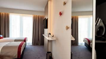 Habitación de hotel con dos camas, un escritorio, un televisor y un cesto de basura.
