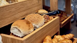 A wooden bread box with various types of bread, including buns and croissants. - Holiday Inn Express Amsterdam - City Hall by IHG (Amsterdam)