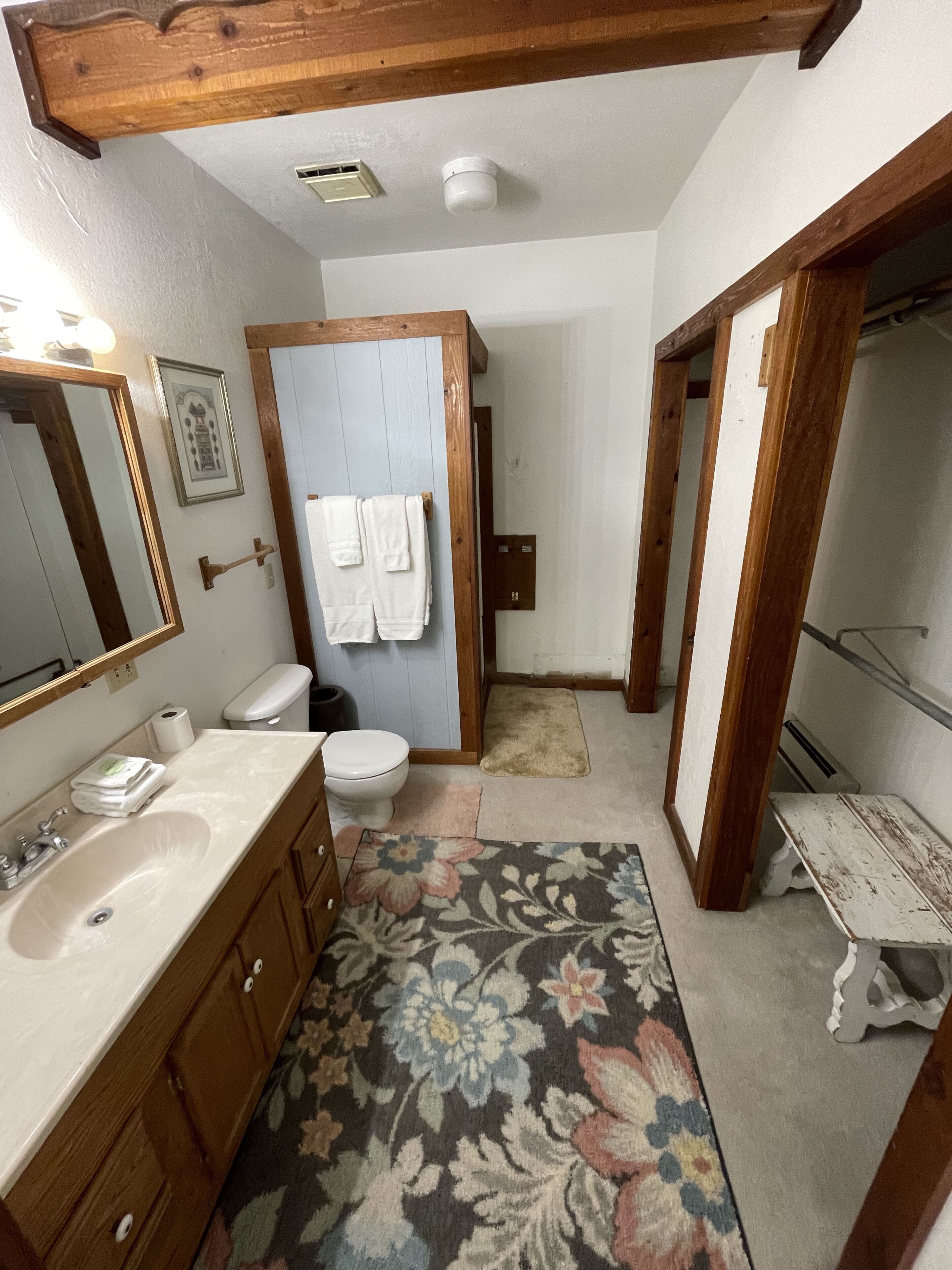 A bathroom with a wooden vanity, a sink, a toilet, and a shower area.