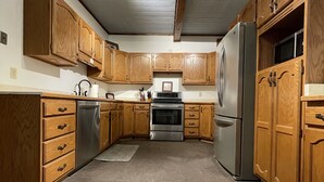 A kitchen with wooden cabinets, stainless steel appliances, and a central island. - Adventures Vacation Rentals (Lava Hot Springs)