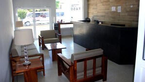 Un área de recepción con un mostrador de madera, un sofá, una mesa y una lámpara.