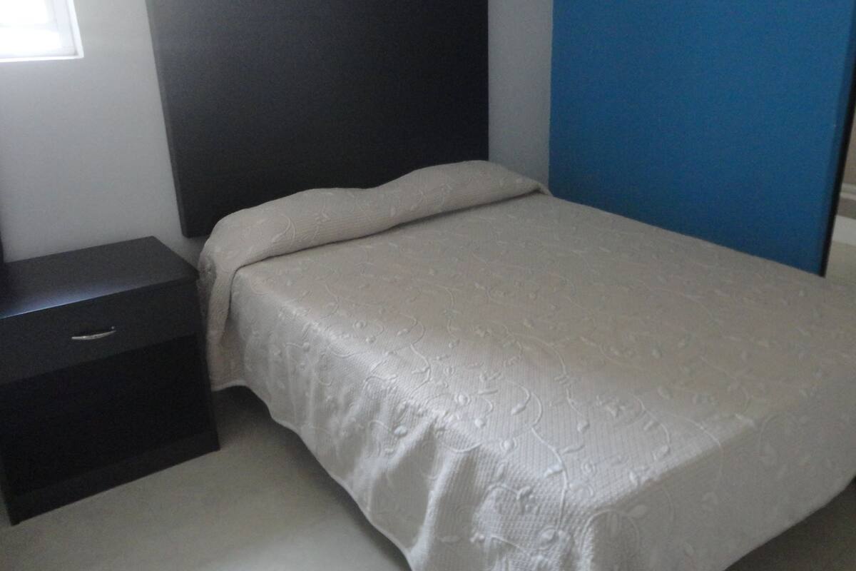 A bedroom with a bed, a nightstand, and a blue wall.