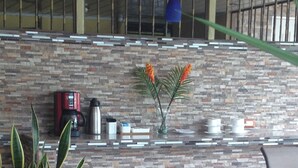 Un espacio moderno de sala con una pared de piedra, un sofá, una cafetera y un florero con flores.