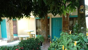 Un patio con un muro de piedra, una puerta azul y una mesa pequeña.