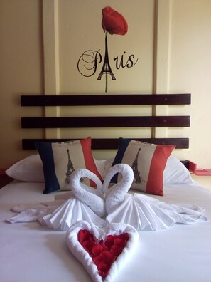 A hotel room with a bed featuring a Paris-themed headboard, pillows with Eiffel Tower designs, and a decorative swan made of towels. - Hotel Boutique Malibu Los Sueños (Puerto Viejo)