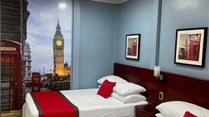 Habitación de hotel con dos camas, una colcha roja y blanca, y un mural del Big Ben al fondo.