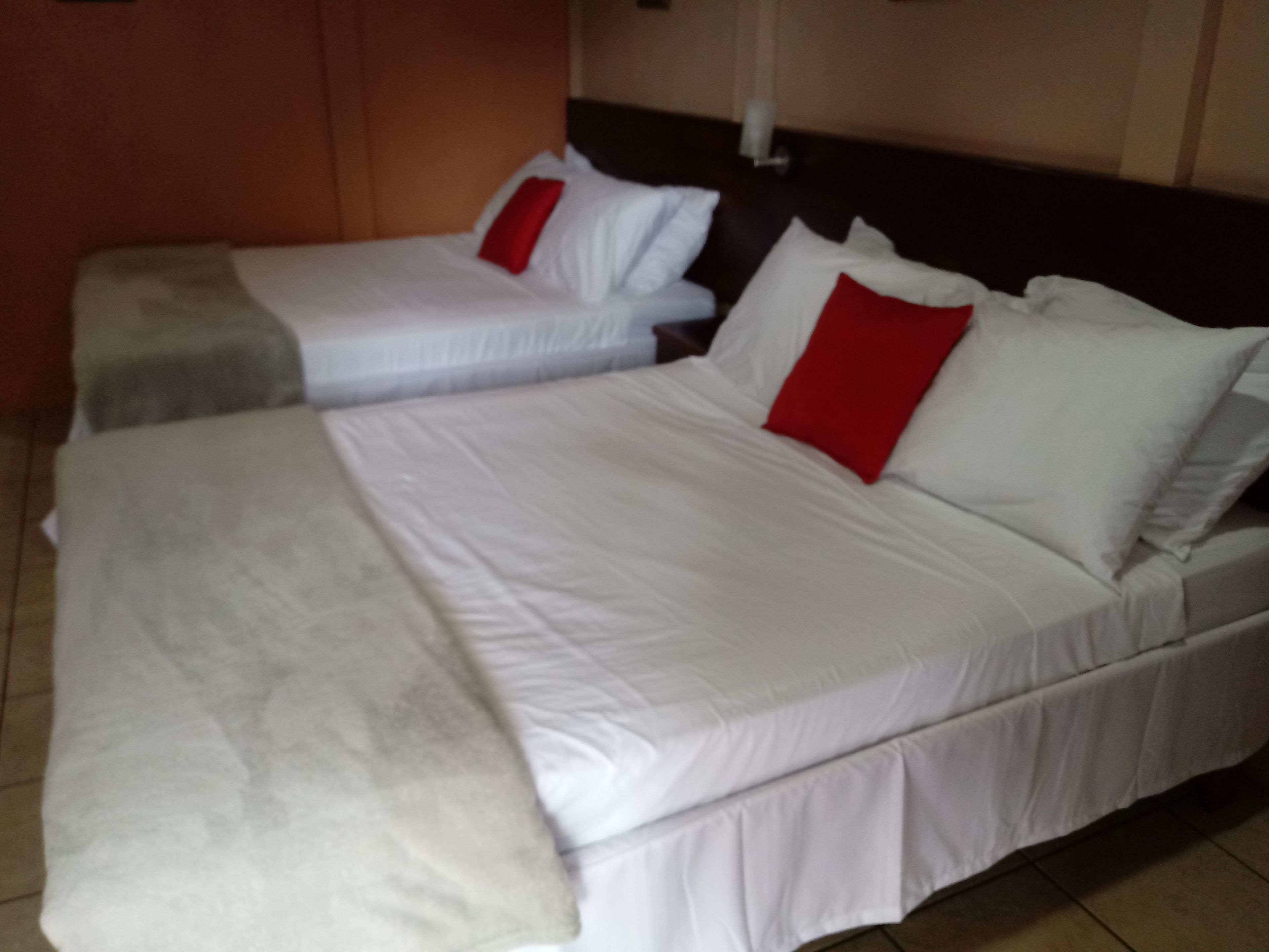 A hotel room with two single beds and one double bed.