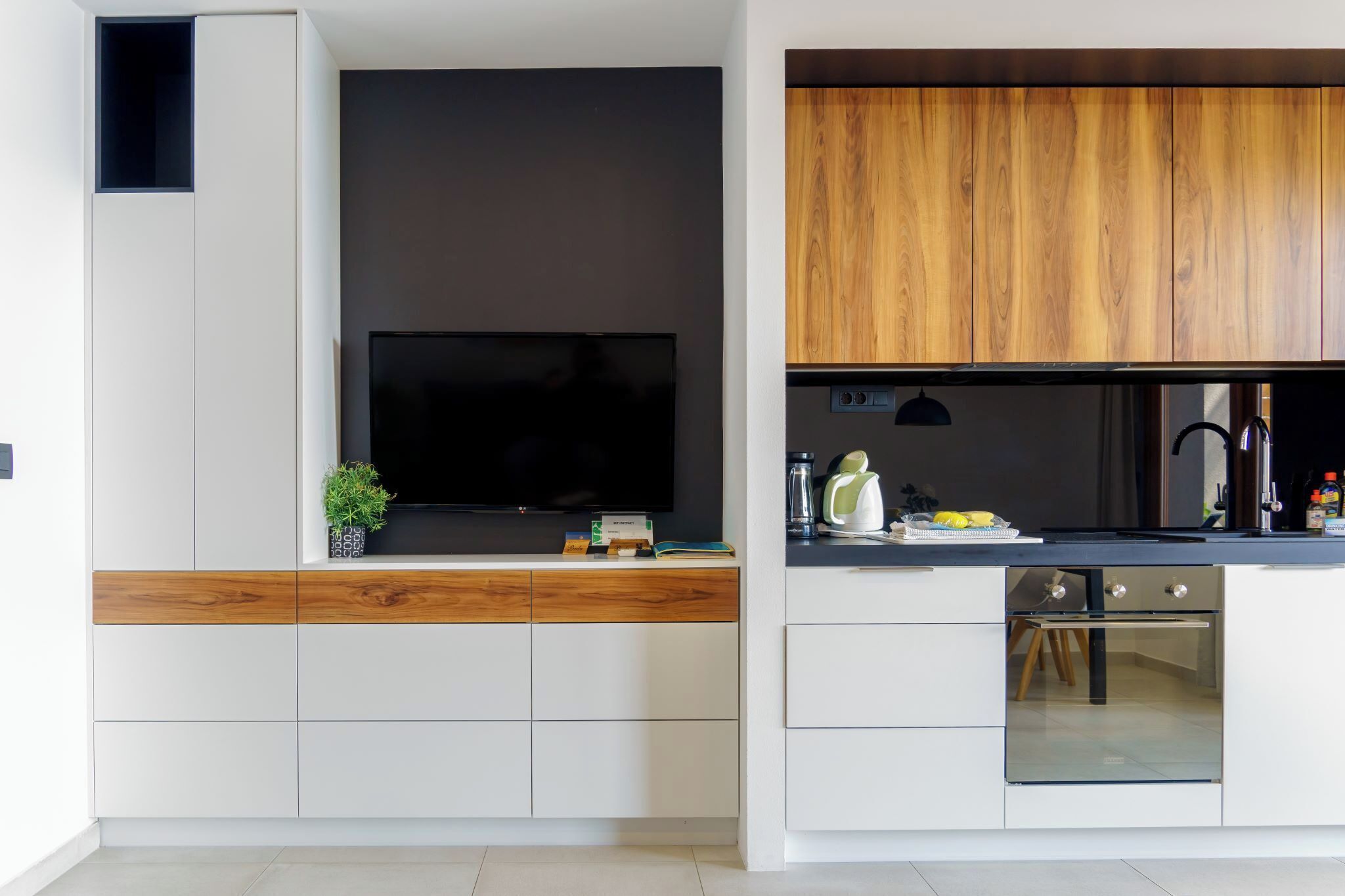 A modern kitchen with a built-in TV, wooden cabinets, and a dishwasher.