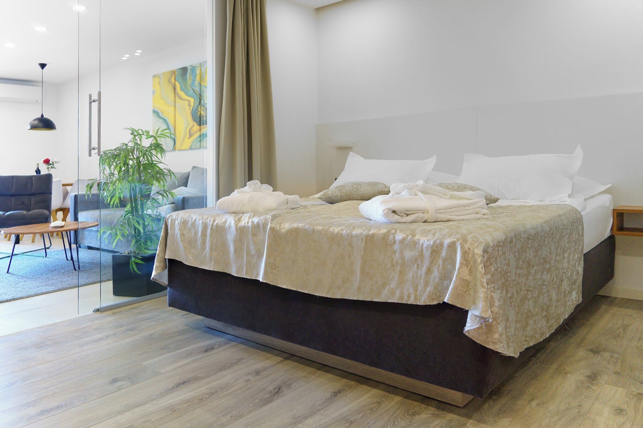 Une chambre d’hôtel moderne avec un grand lit, un canapé, une table à manger et une plante en pot.