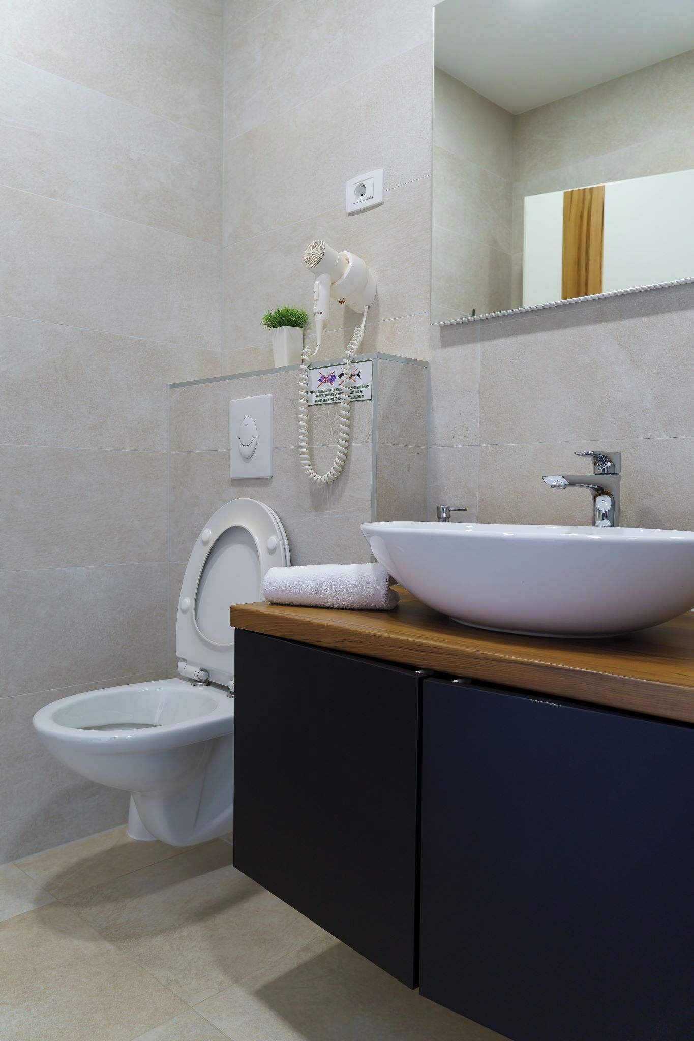 Une salle de bain moderne équipée de toilettes, d’un bidet et d’un lavabo doté d’un plan de travail en bois.
