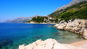 A coastal town with clear blue waters, rocky shores, and buildings on a hillside. - Apartments Bikin (Brela)