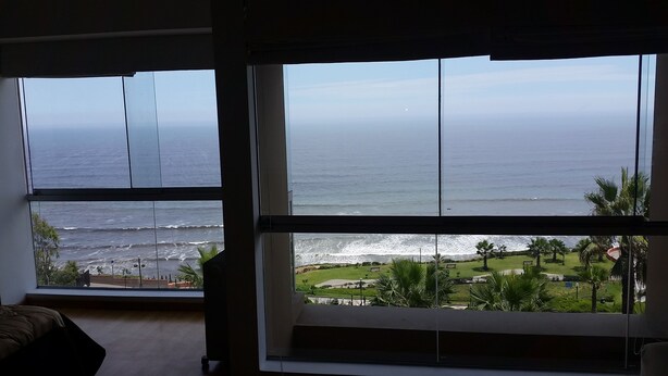 Una habitación con amplios ventanales con vistas a una playa y al océano.