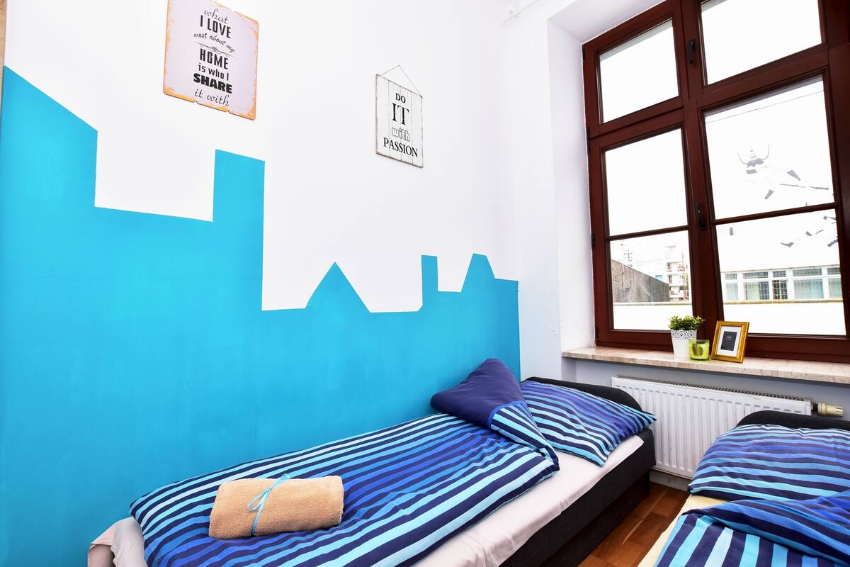 Une chambre avec deux lits, une fenêtre offrant une belle vue et des œuvres d’art murales inspirantes.
