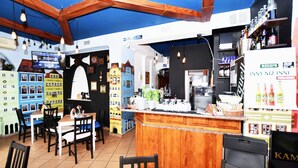 Un restaurant doté d’un bar en bois, de tables, de chaises et d’une maquette colorée représentant une maison de jeu.