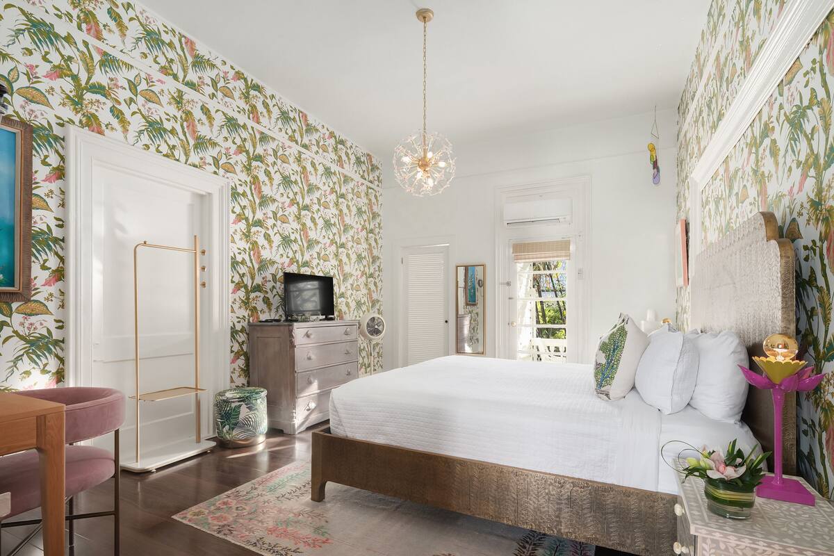 A bedroom with a bed, dresser, and a television.