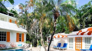 A pool area with lounge chairs and a small palm tree. - Marrero's Guest Mansion (Key West)