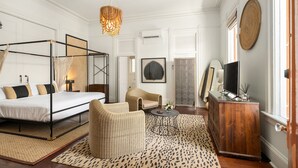 A bedroom with a four-poster bed, a wicker chair, a wooden dresser, and a television. - Marrero's Guest Mansion (Key West)