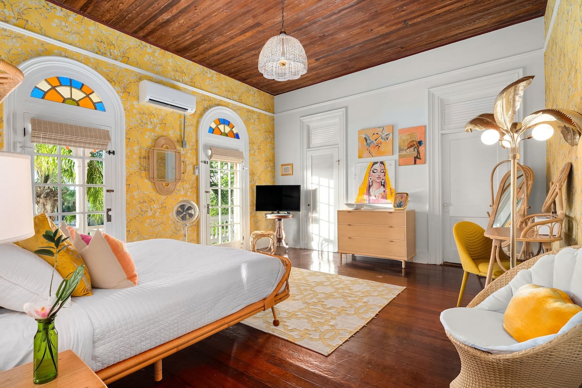 A room with a bed, a desk, a chair, a television, and a decorative lamp.