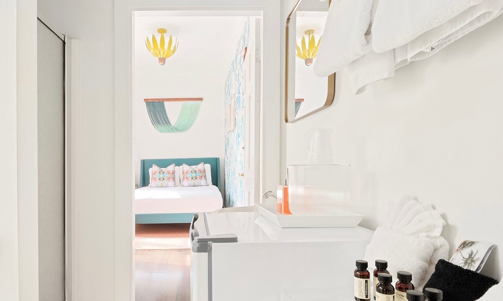 Une salle de bain moderne avec un lavabo blanc, un miroir et un espace douche. On trouve des articles de toilette sur le comptoir et une serviette est accrochée au mur.