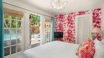Ein Schlafzimmer mit Bett, Fernseher, Blick auf einen Pool und tropischem Wandpapier.
