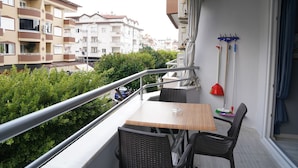 A balcony with a table and chairs, a railing, and a view of neighboring buildings. - Alanya Polat Tatil Evleri (Alanya)