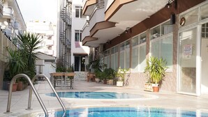 A swimming pool with a sun terrace, surrounded by potted plants and a stone wall. - Alanya Polat Tatil Evleri (Alanya)