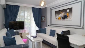 A modern living room with a sofa, a coffee table, and a TV. - Alanya Polat Tatil Evleri (Alanya)
