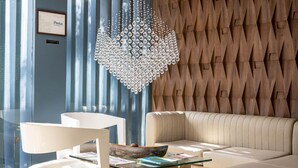 A modern living room with a glass coffee table, a beige sofa, and a decorative chandelier. - Hotel Perla Suite Santa Marta (Santa Marta)