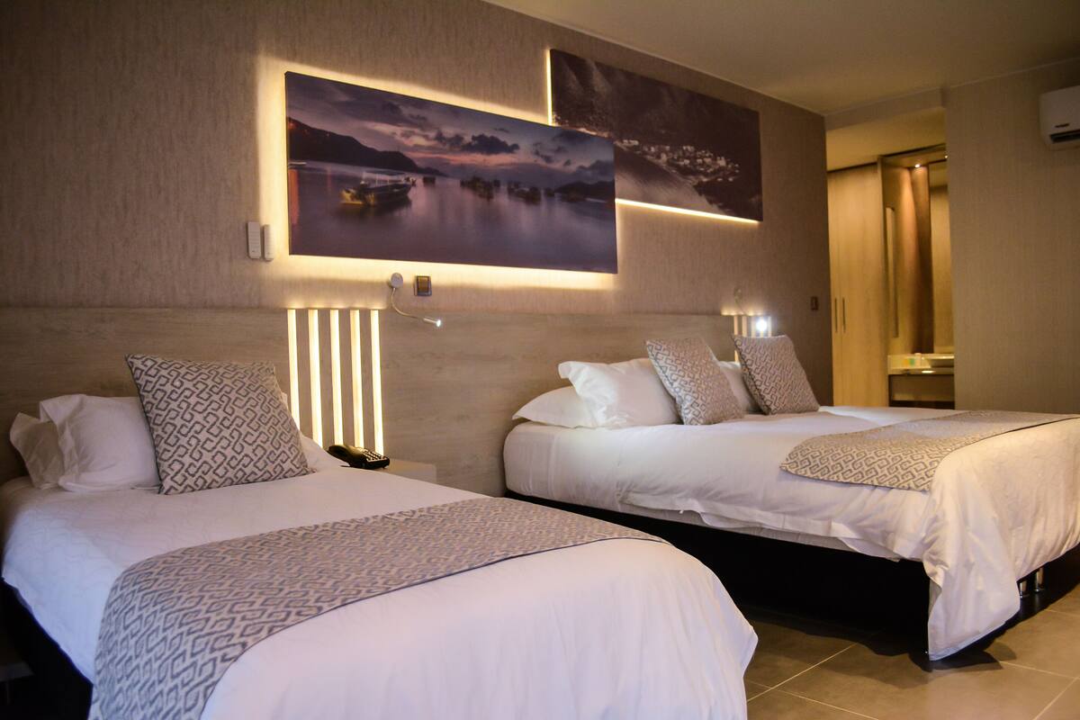 Two beds with patterned bedding, a nightstand, and wall-mounted artwork.