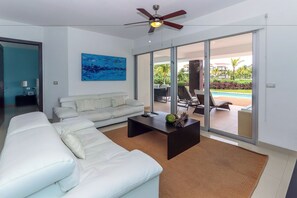 A modern living room with a white sofa, a dark coffee table, and a ceiling fan. - Agua Dulce by NAS (Playa del Carmen)