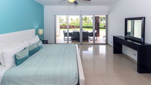 Un dormitorio con cama, televisión y puerta corrediza de vidrio que da a un área exterior con mesa y sillas.