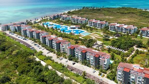 Vista aérea de un resort con varias edificaciones, una piscina y una playa.