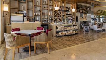 A cafe with a wooden interior, a coffee machine, wicker chairs, and shelves with various items.