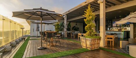 An outdoor patio with wooden flooring, a bar area, and outdoor seating.