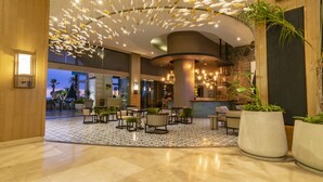 A spacious lobby with a modern chandelier, seating area, and a large potted plant.