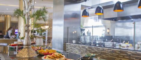 A buffet with various dishes, a decorative silver vase, and a kitchen area in the background.