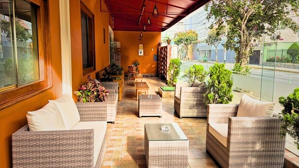 A covered outdoor seating area with wicker furniture and potted plants. - Hotel Tinkus Inn (Lima)