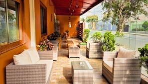 Un espacio de estar al aire libre techado con mobiliario de mimbre y plantas en macetas.