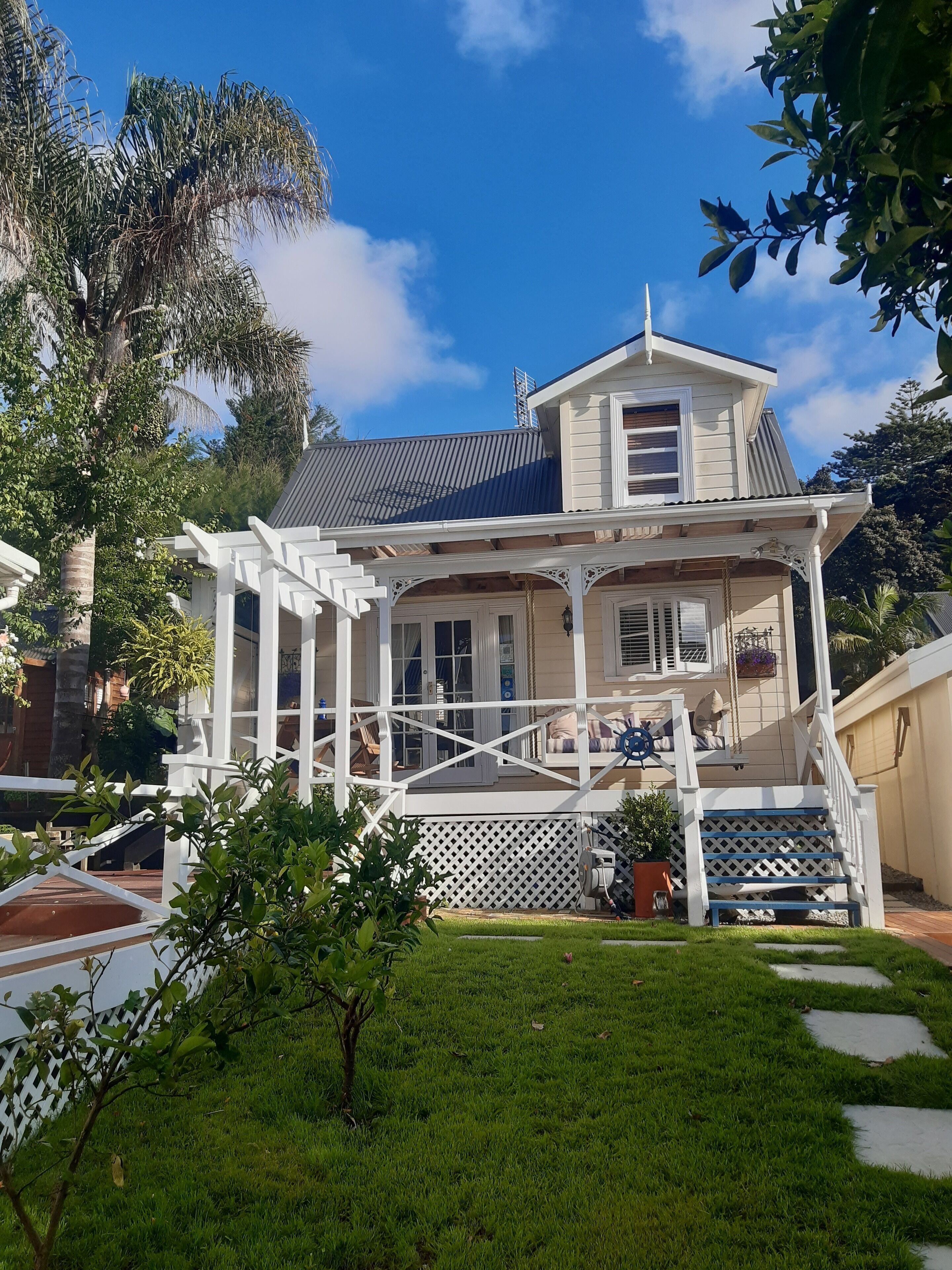 A two-story house with a porch, a small garden, and a white fence.