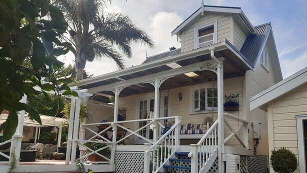 Une maison à deux étages avec un porche couvert, un escalier et un petit jardin.